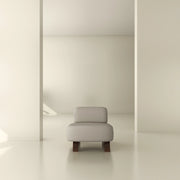 Modern minimalist lounge chair with light upholstery and wooden legs in a neutral interior setting